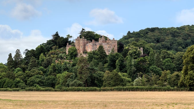 Exterior of Dunster Castle, Somerset, from the main road on a day with blue skies.